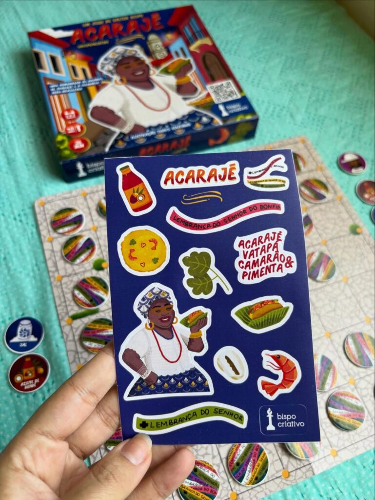 Cartela de adesivos do jogo de tabuleiro Acarajé com ilustração de baiana e elementos da culinária afro-brasileira